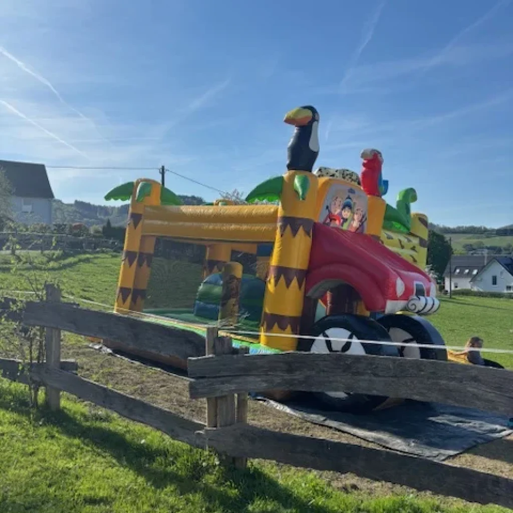Bunte aufblasbare Hüpfburg in Form eines Fahrzeugs mit Tieren auf dem Dach.